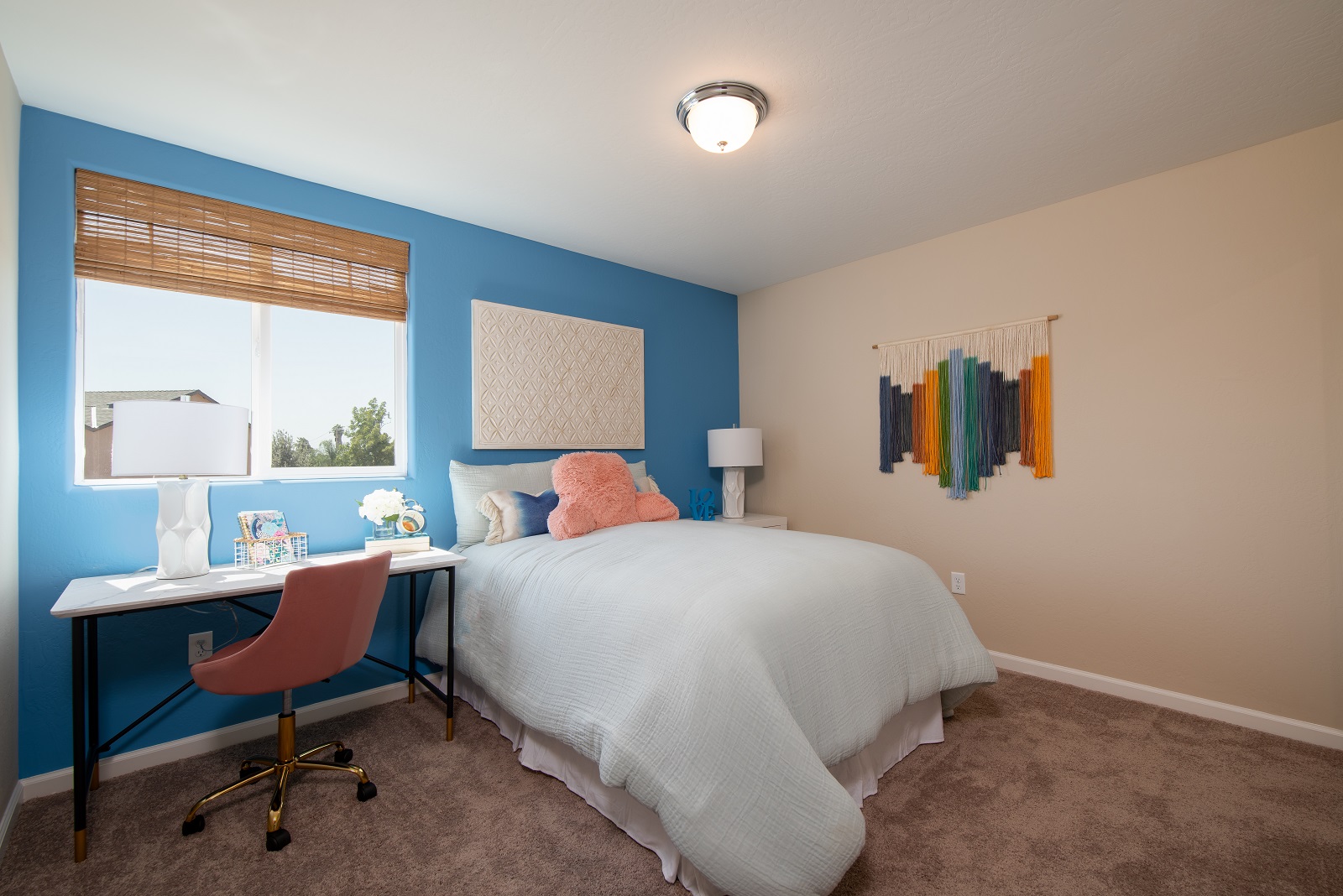 A bedroom with a bed desk and a chair.