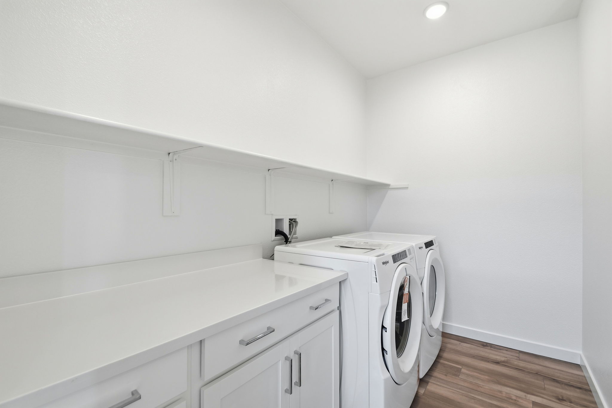 A white kitchen with a stove and a white counter top.