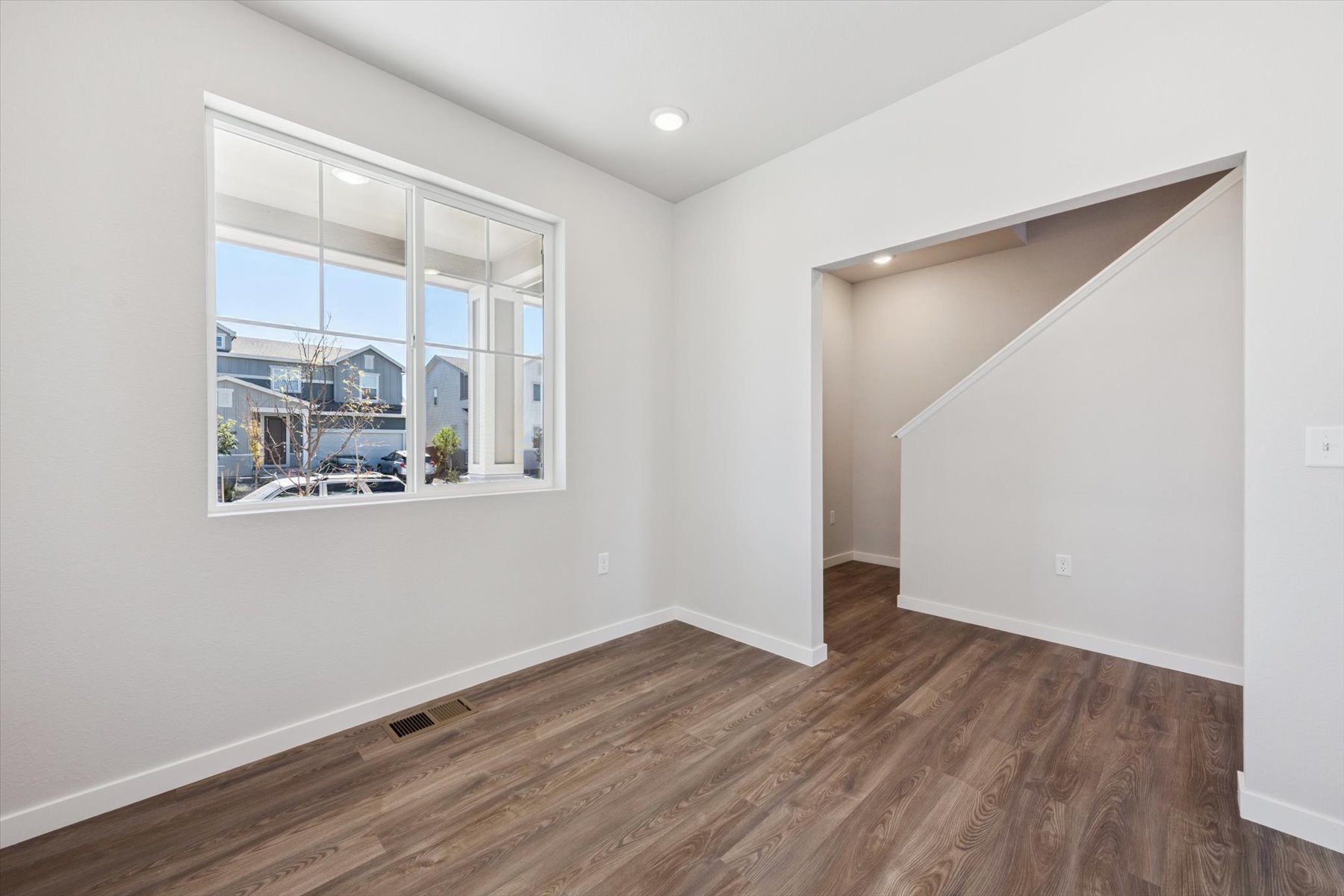 A room with a wood floor and a window with a view of the city.