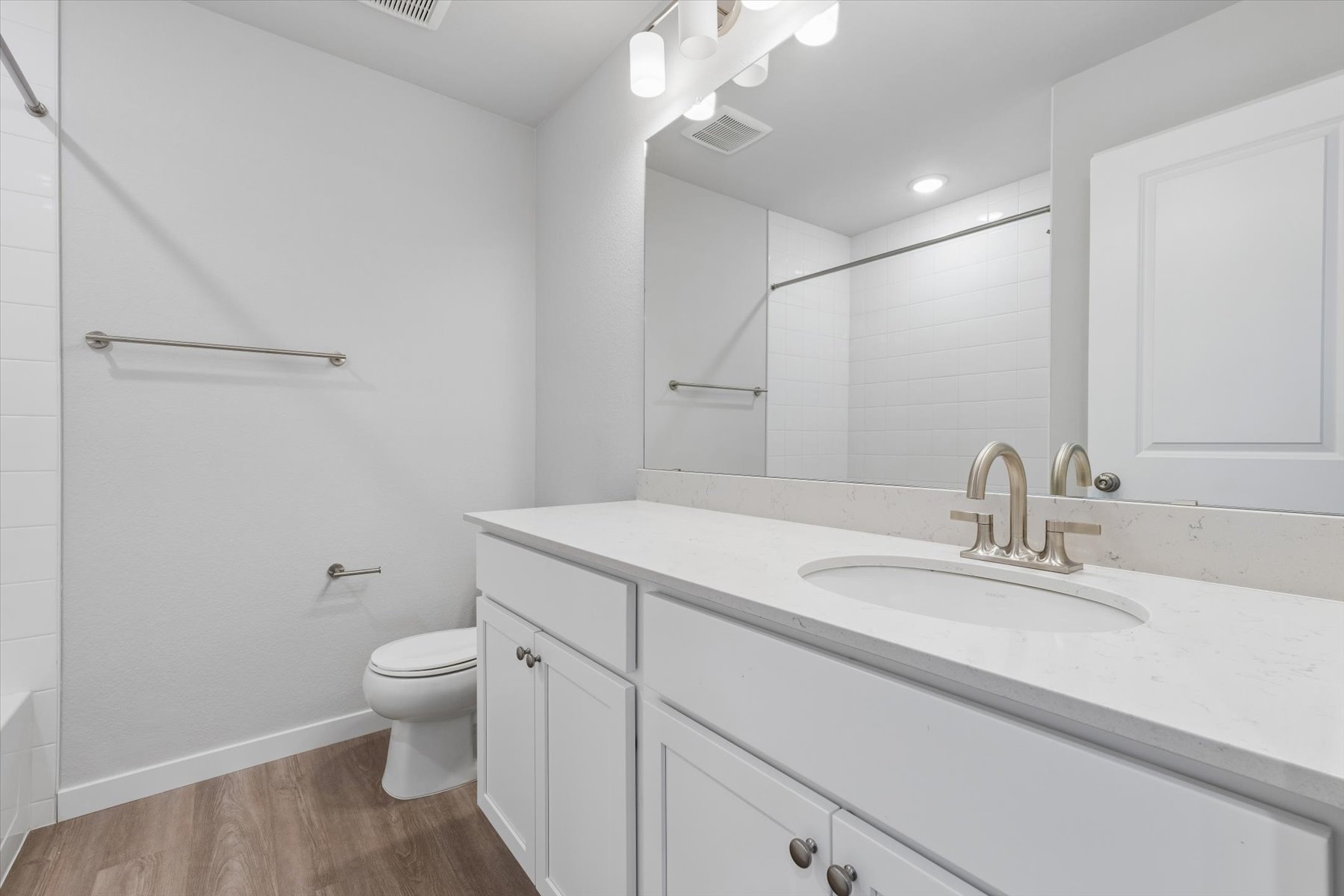 A bathroom with a sink toilet and mirror.