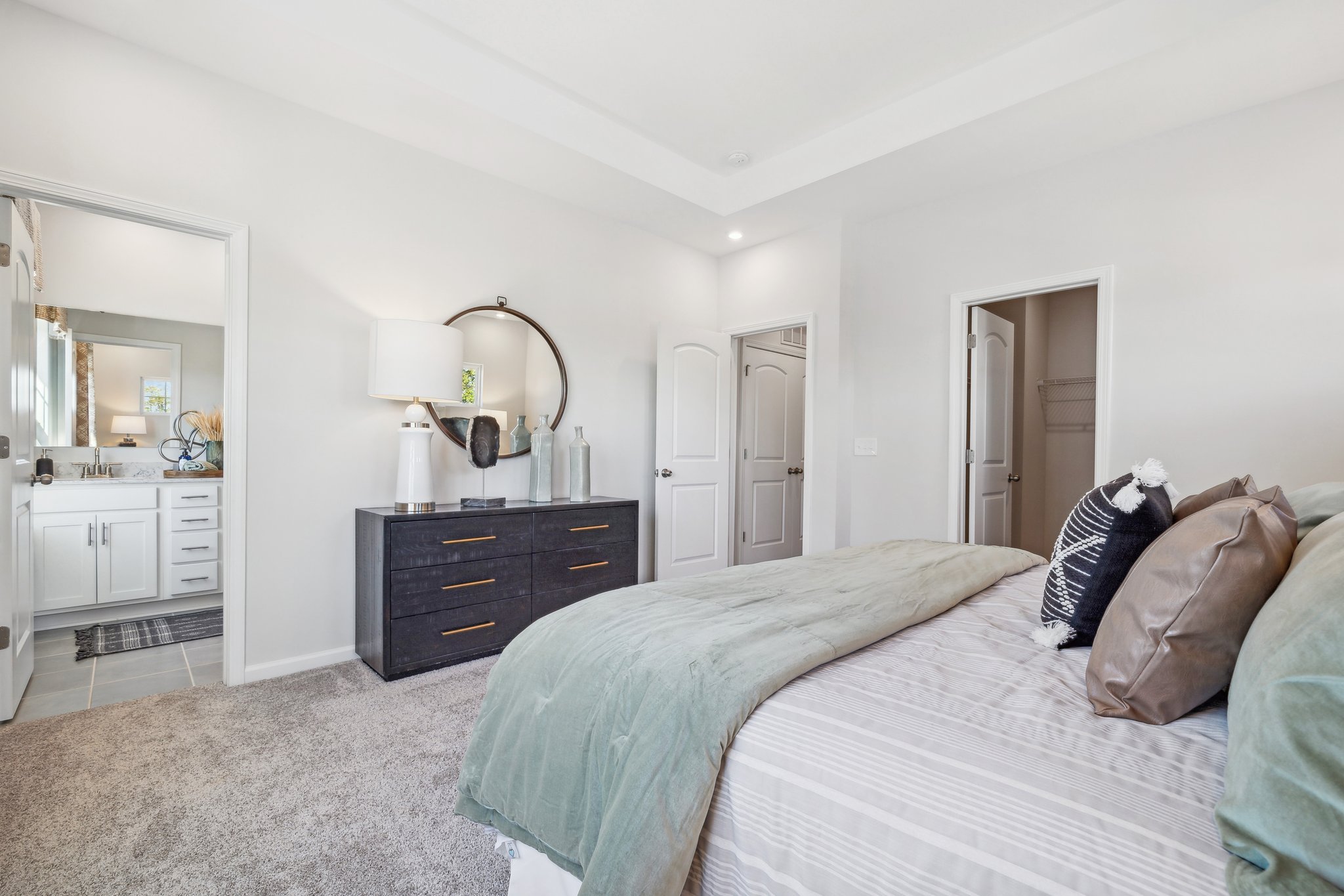 A bedroom with a bed and a mirror.