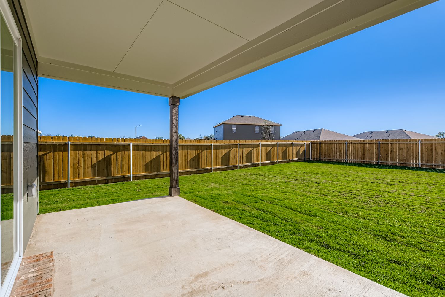 A fenced in area with a walkway and grass and a building in the background.