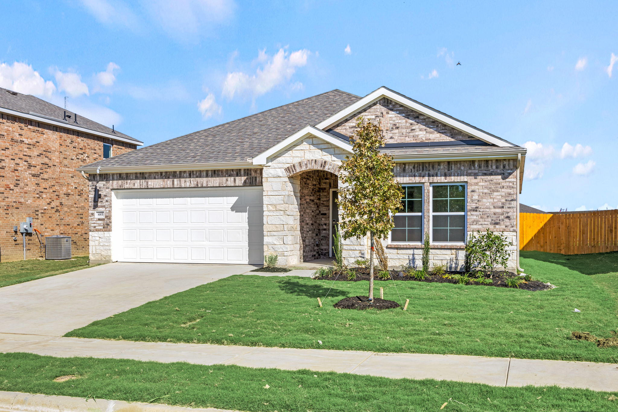 A house with a garage and a tree in the front.