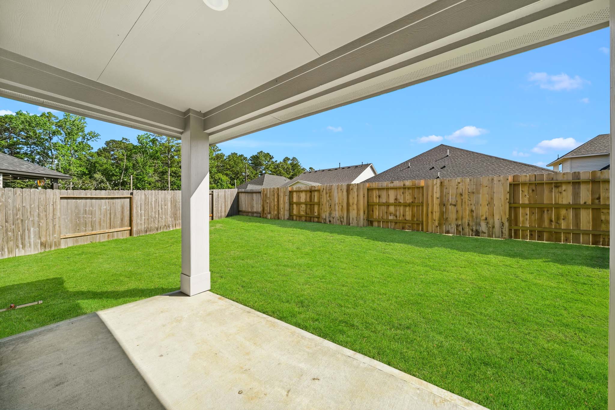 A fenced in yard with a covered area and a house.