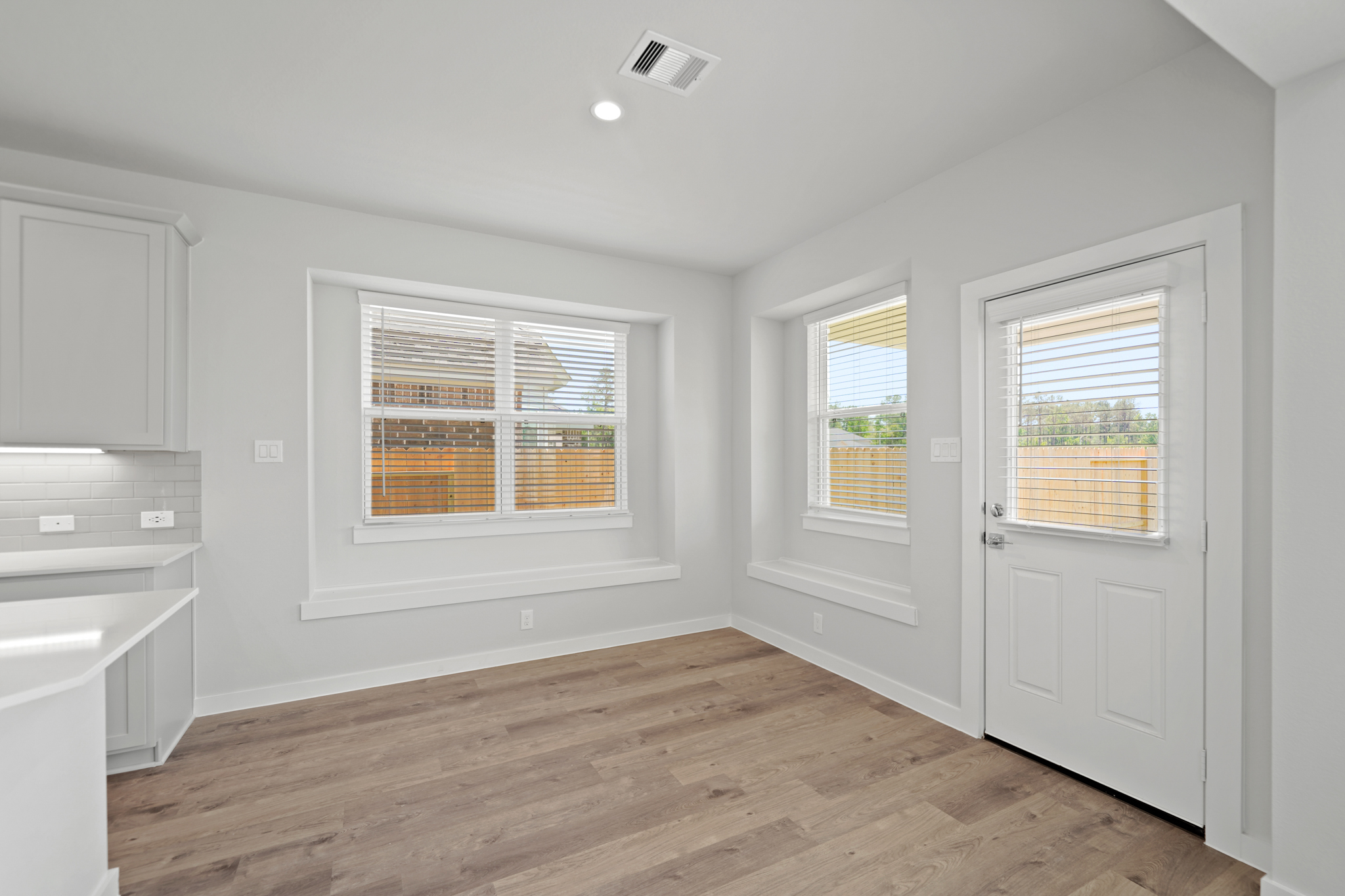 A room with white cabinets and a wood floor.