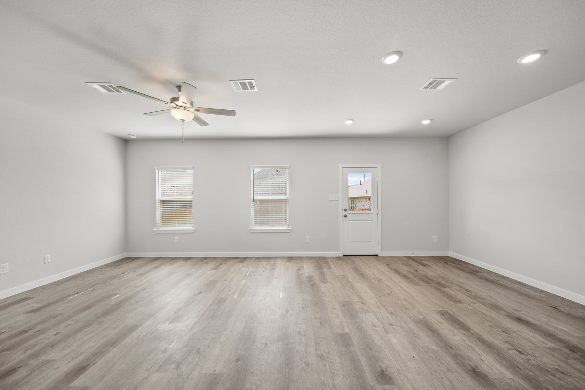A room with a ceiling fan and a wood floor.