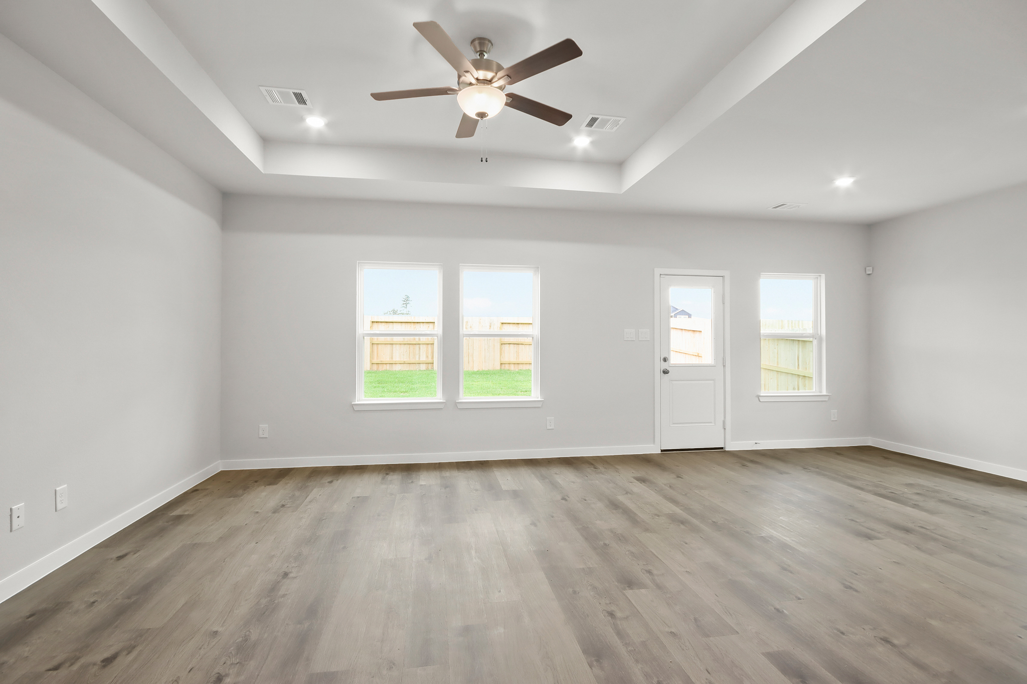 A room with a wood floor and a ceiling fan and a wood floor.