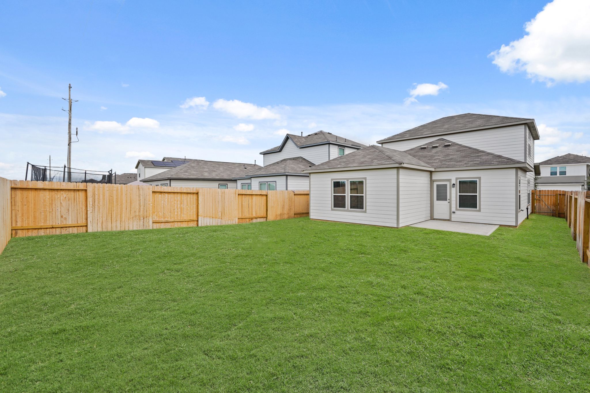 A fenced in yard with a house in the background.