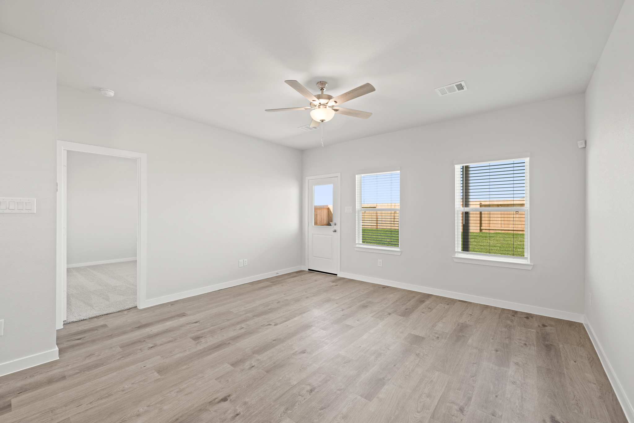 A room with a wood floor and a ceiling fan.