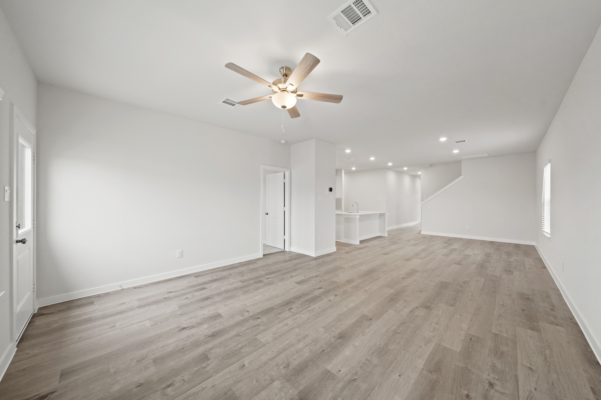 A room with a ceiling fan and wood floors.
