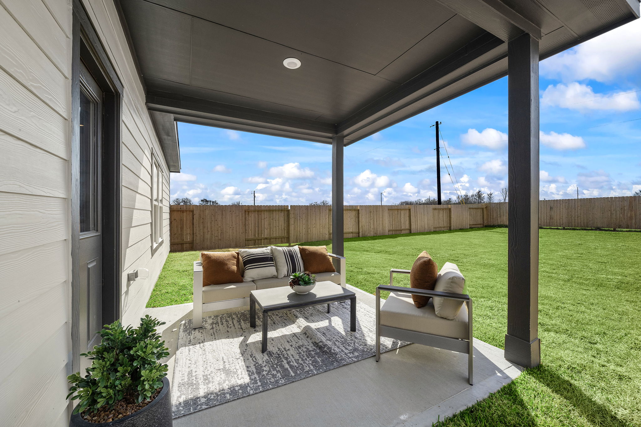A deck with a table and chairs and a large window with a view of a field and a.