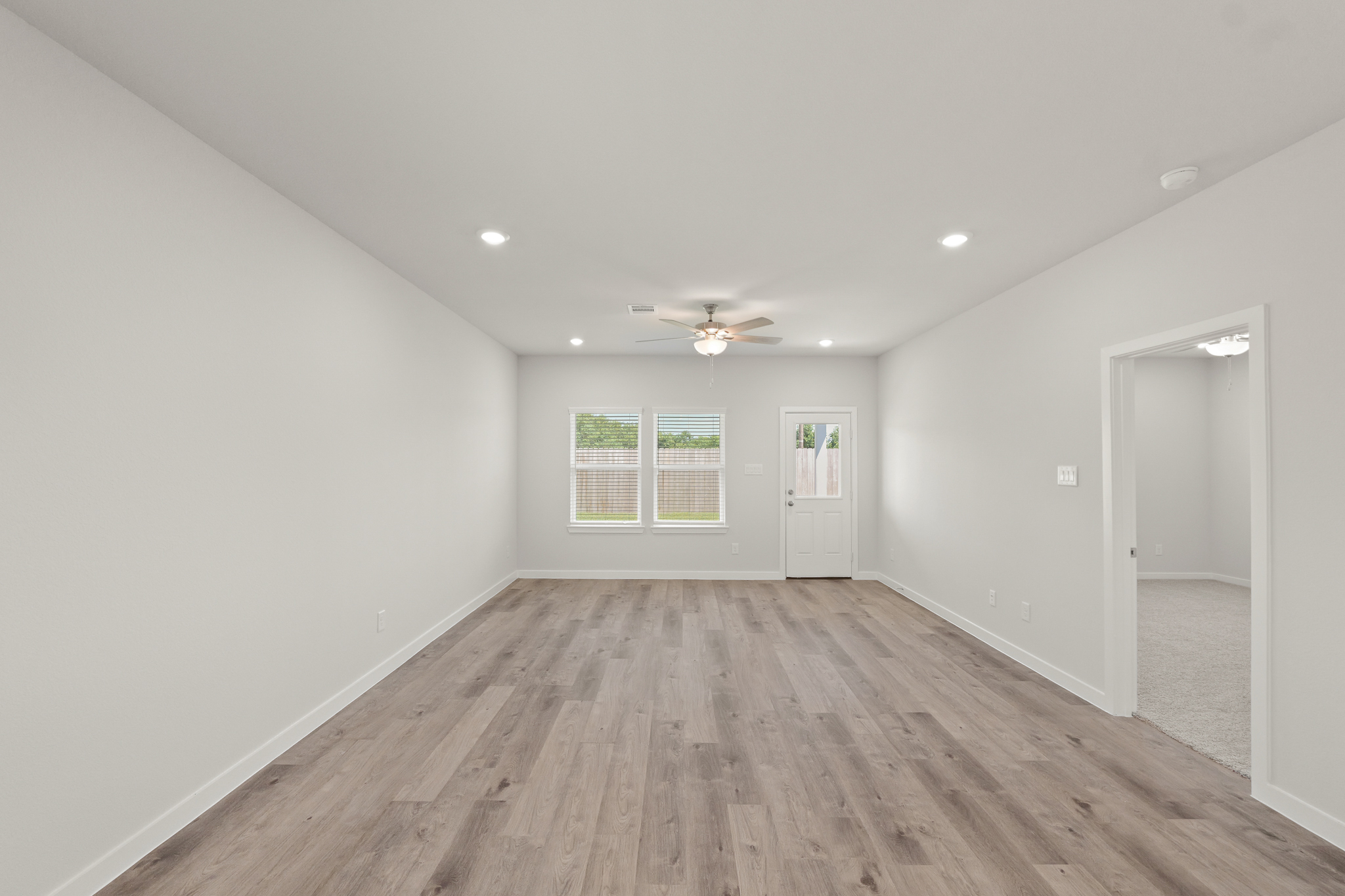 A room with a wood floor and a wood floor with a ceiling fan.
