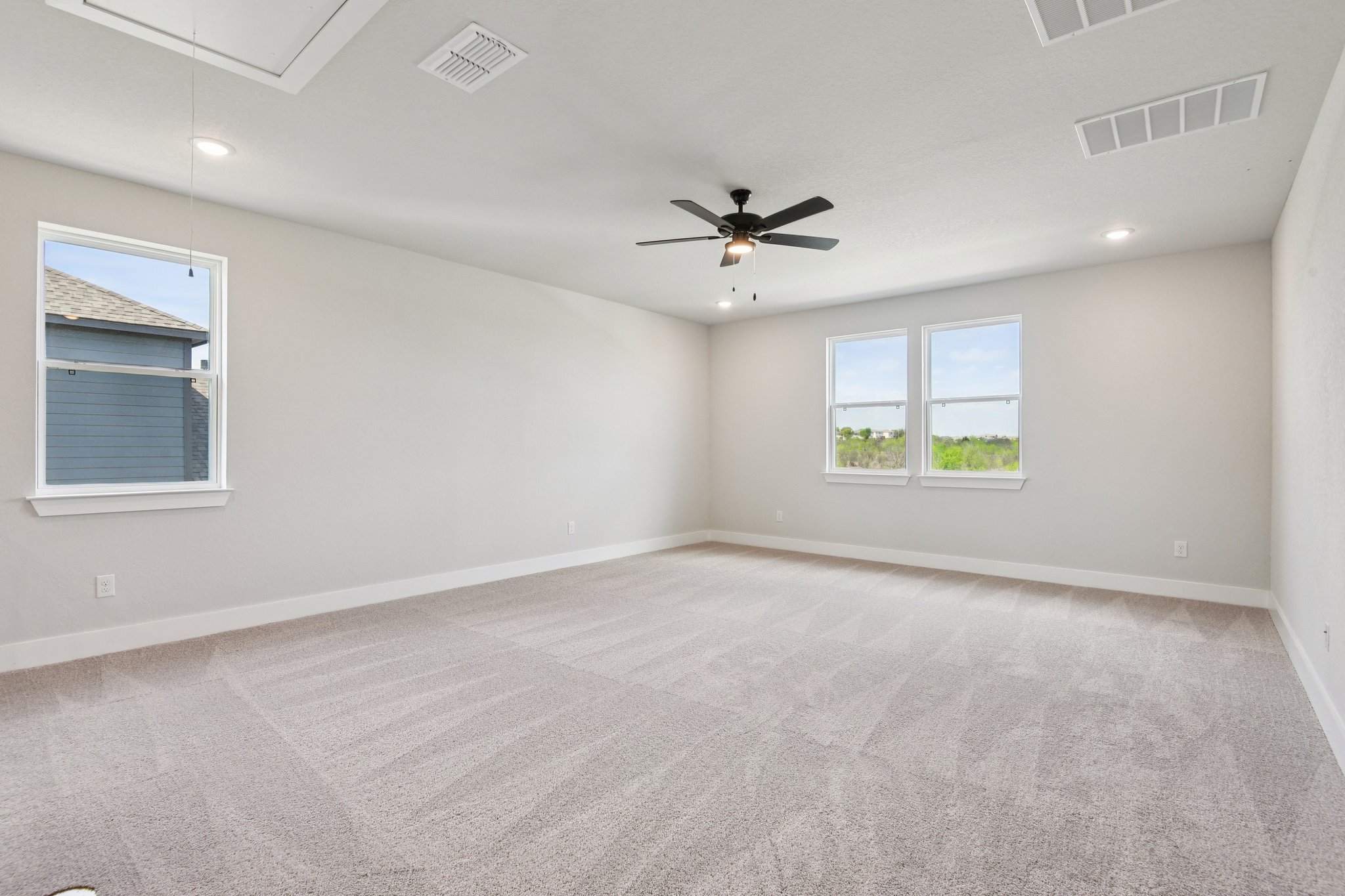 A room with a ceiling fan and a carpet.