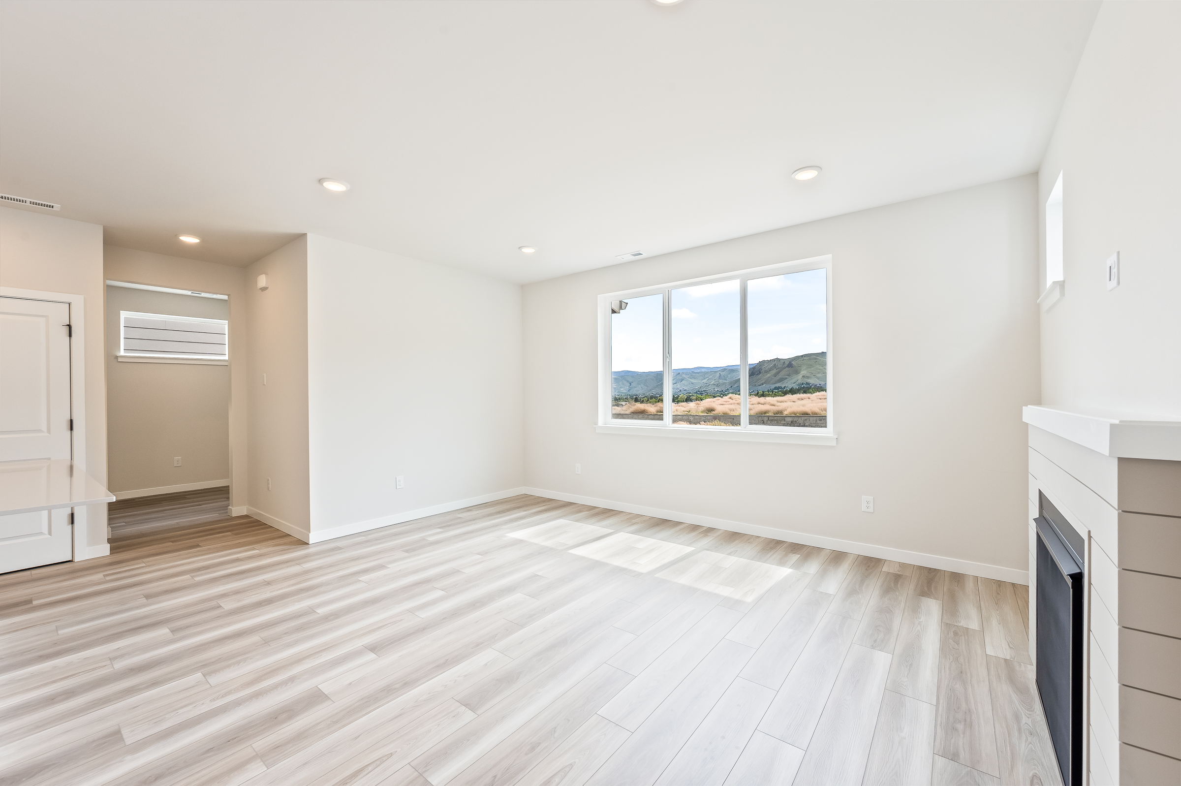A large empty room with a wood floor and a window.
