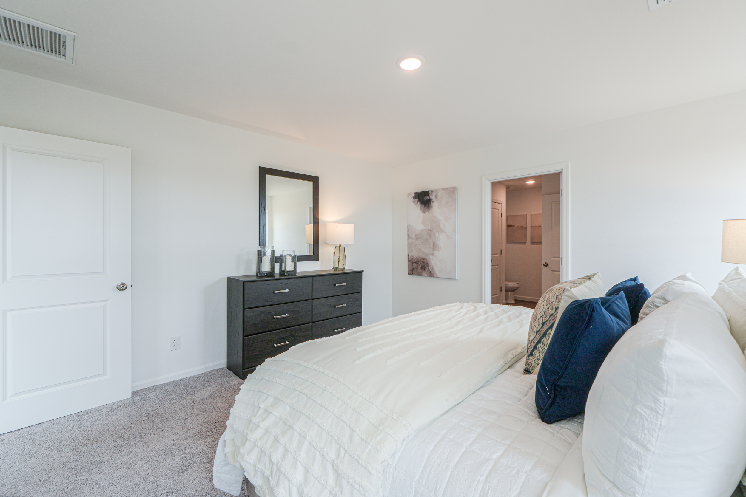 A bedroom with a bed and dresser.