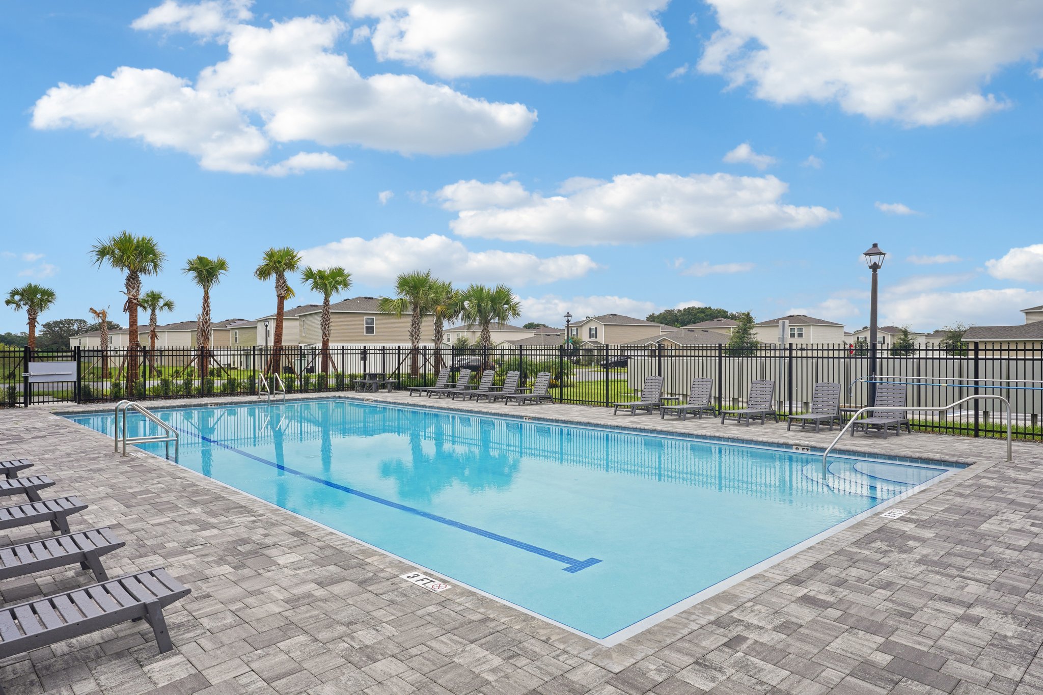 A swimming pool with trees and a fence around it.