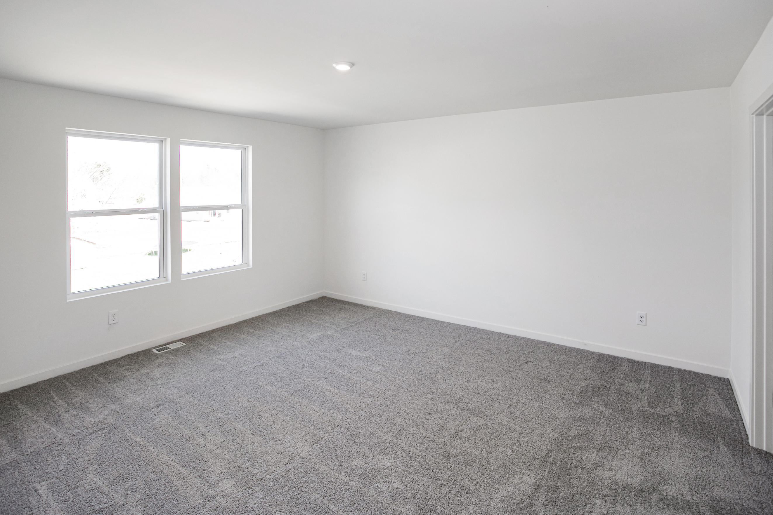 A room with a carpet and windows.