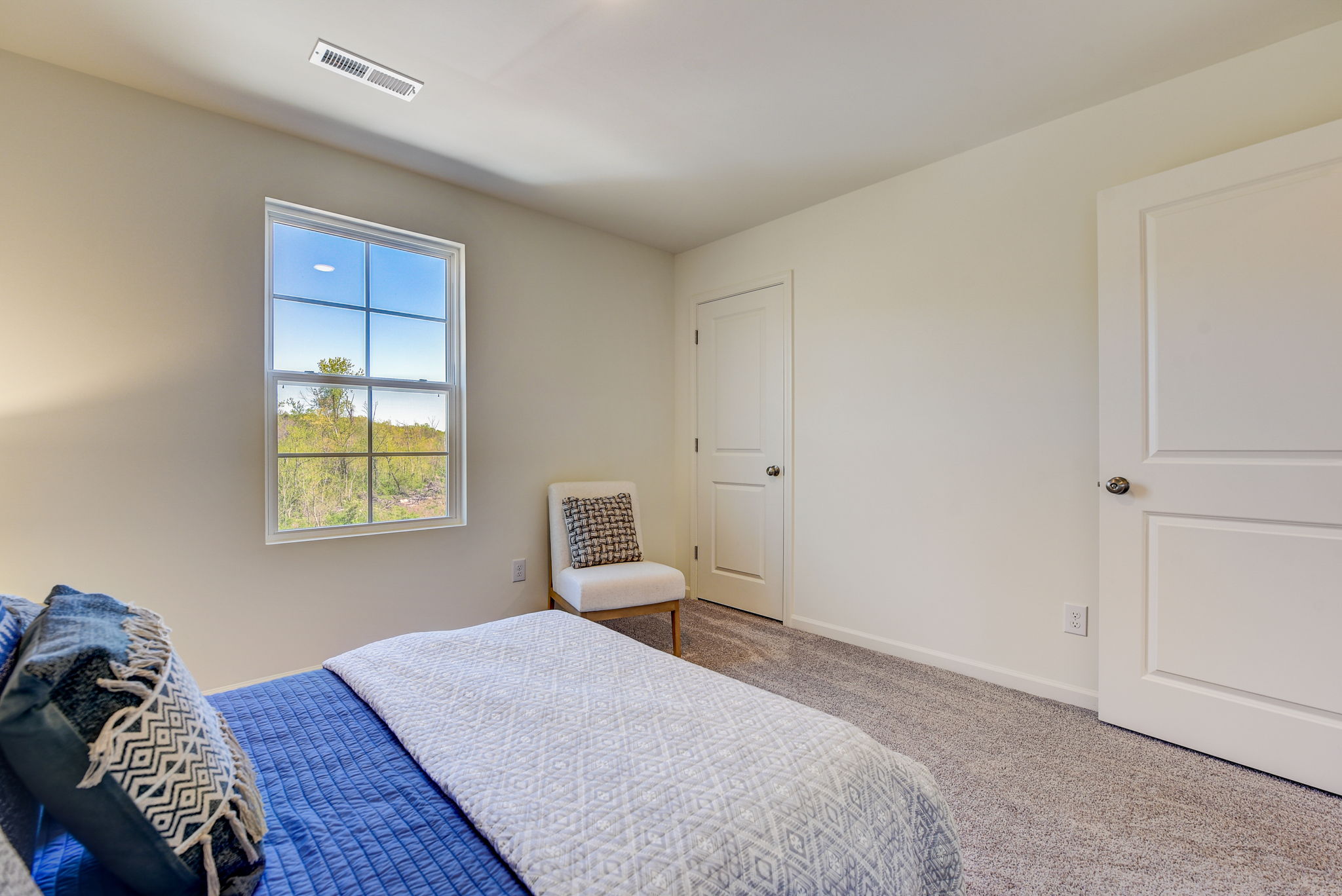 A bedroom with a chair and a bed.